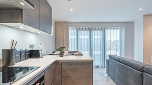 Een moderne keuken met een keukeneiland, inbouwapparatuur en een zithoek met een bank.