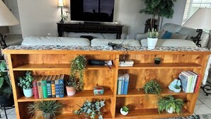 Ein Holzregal mit Pflanzen, Büchern und einem Fernseher in einem Wohnzimmer.