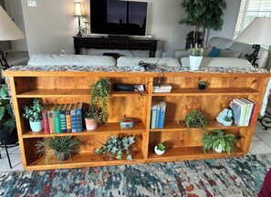 Ein Holzregal mit Pflanzen, Büchern und einem Fernseher in einem Wohnzimmer.