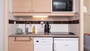 A compact kitchen with a microwave, coffee maker, and dishwasher. - "Arzon" Apartment with Terrace, Shared Pool and Communal Garden (Arzon)