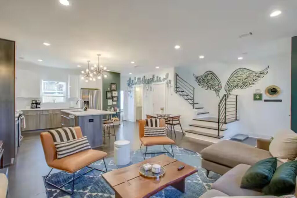 A modern living room with a sofa, armchairs, a coffee table, and a dining area with chairs and a table.