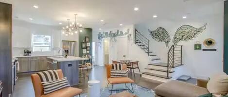 A modern living room with a sofa, armchairs, a coffee table, and a dining area with chairs and a table.