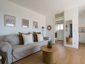Ein modernes Wohnzimmer mit einer Couch, einem runden Holztisch und einer Duschwand aus Glas.