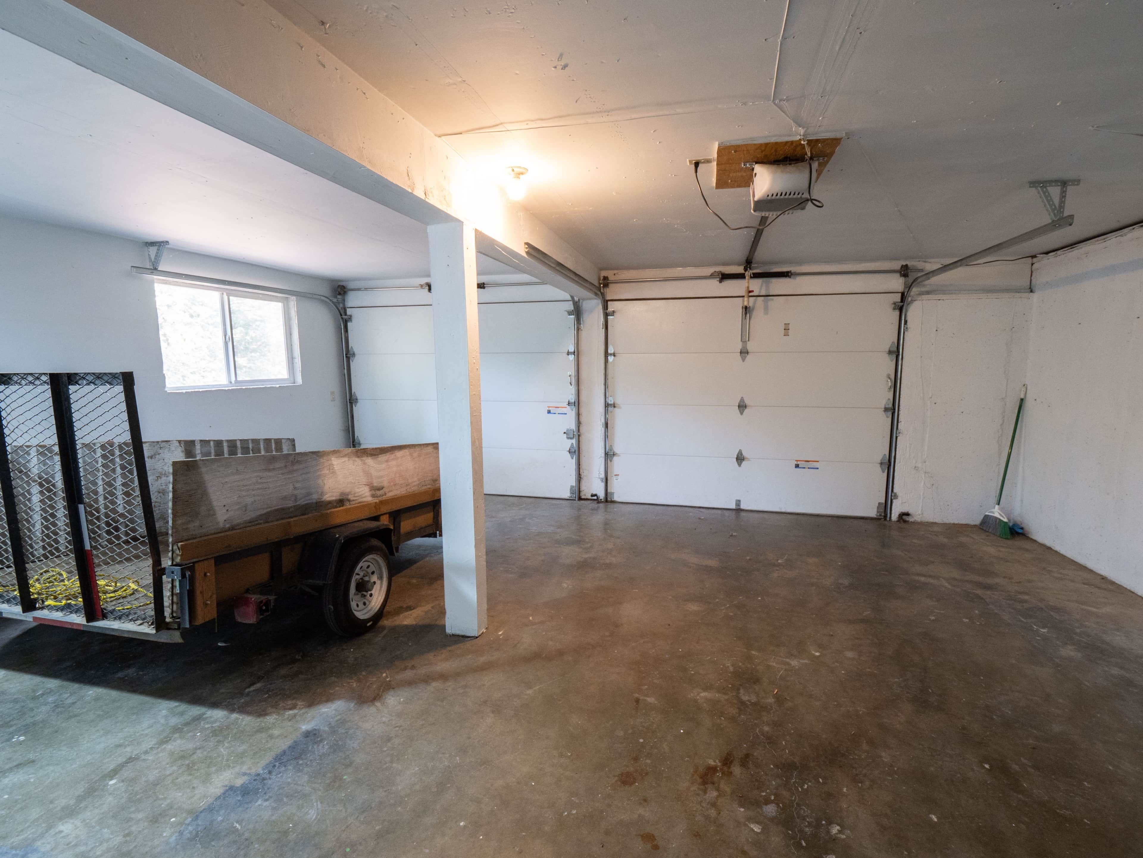 Eine Garage mit einem Lastwagen, Betonboden und weißen Garagentüren.