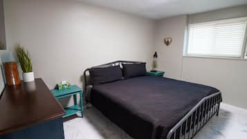 Un dormitorio con una cama, un escritorio, una lámpara, una planta en maceta y una ventana con persianas.