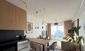 Een moderne keuken met een eethoek, een flatscreen-tv en een groot raam met uitzicht op de stad.