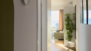 Ein modernes Interieur mit Holzboden, einer Tür zum Balkon, einer Pflanze und einem gerahmten Bild an der Wand.