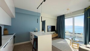 Eine moderne Küche mit Kochinsel, ein Essbereich mit Aussicht und ein Wohnbereich mit Fernseher.