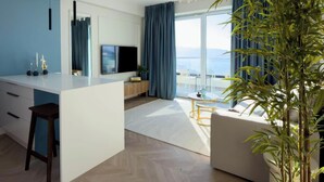 Ein moderner Wohnraum mit Küche, Essbereich und großem Fenster mit Blick auf ein Gewässer.