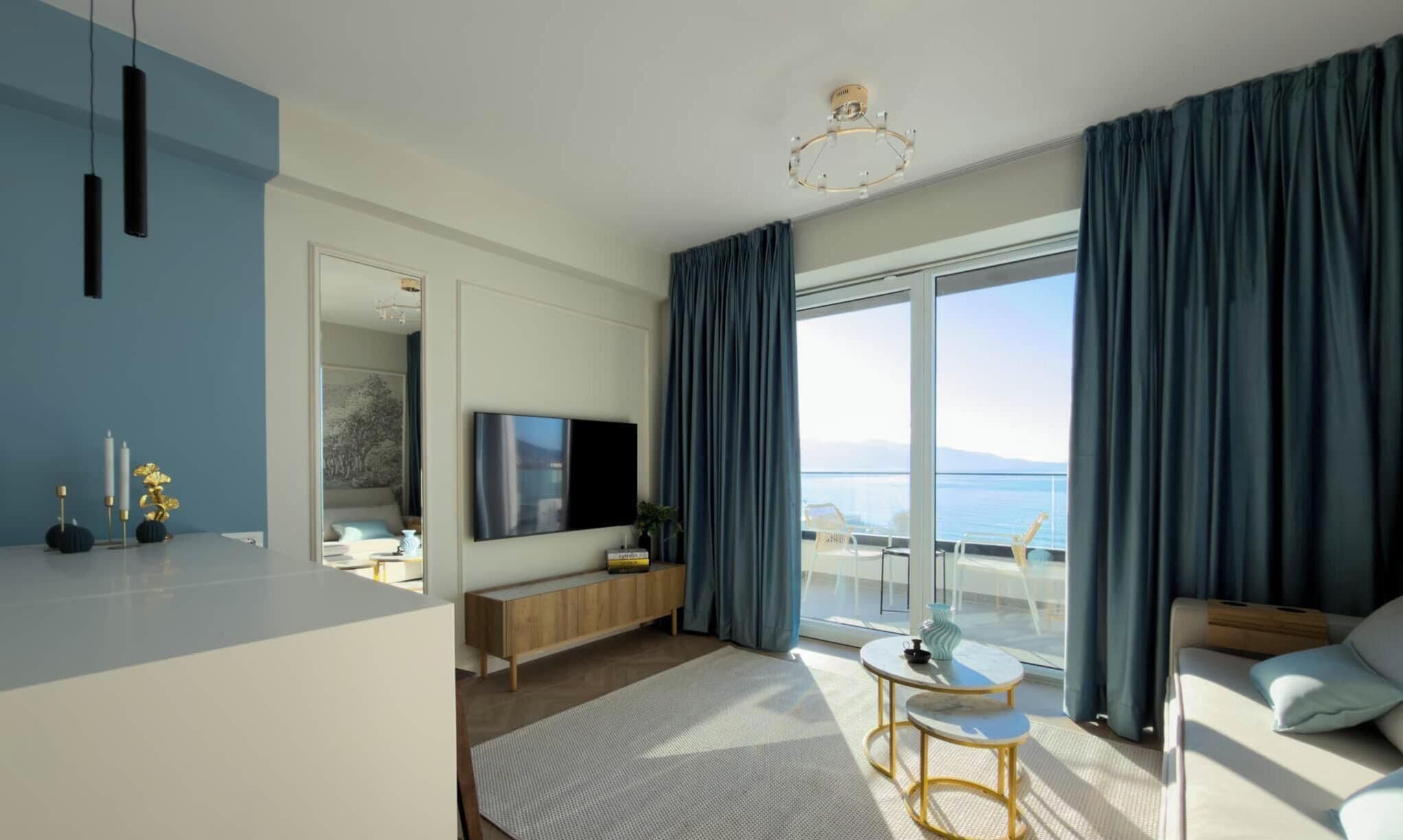 Una habitación de hotel moderna con un balcón grande, un televisor de pantalla plana y una zona de estar acogedora.
