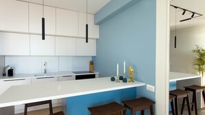 Eine moderne Küche mit weißen Schränken, einer blauen Akzentwand und einer Bar mit Hockern.