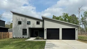A modern two-story house with a garage, a well-maintained lawn, and a clear sky. - House in Conroe (Conroe)