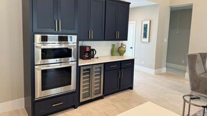 A modern kitchen with dark cabinetry, stainless steel appliances, and a light-colored countertop. - House in Conroe (Conroe)