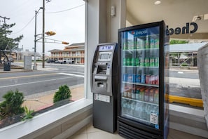 Un distributeur automatique de billets et un distributeur de boissons réfrigérées situés à l’extérieur d’un bâtiment.