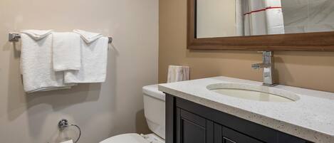 A bathroom with a toilet, sink, and mirror.
