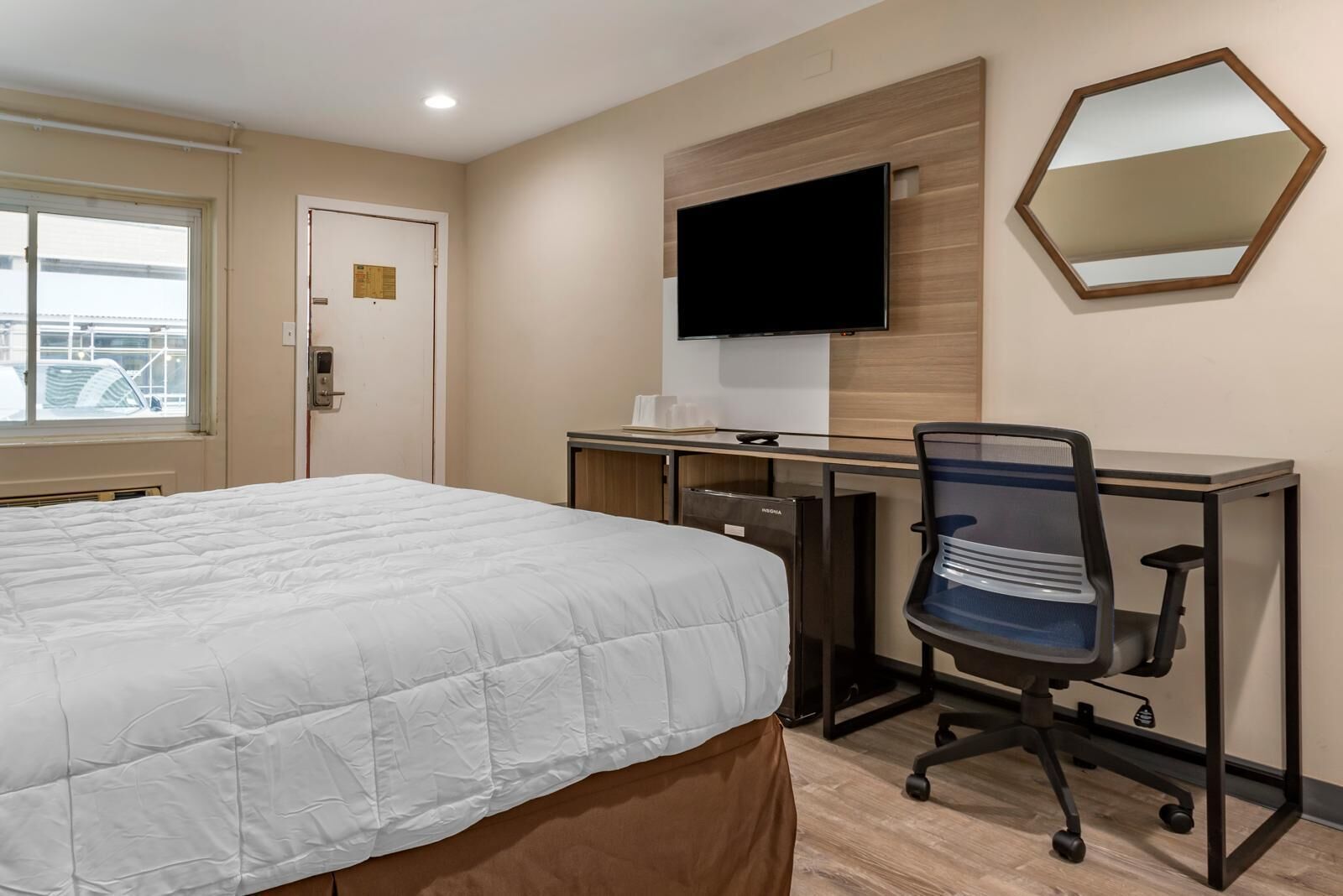 Ein Hotelzimmer mit Bett, Schreibtisch, Stuhl, Fernseher und Fenster.