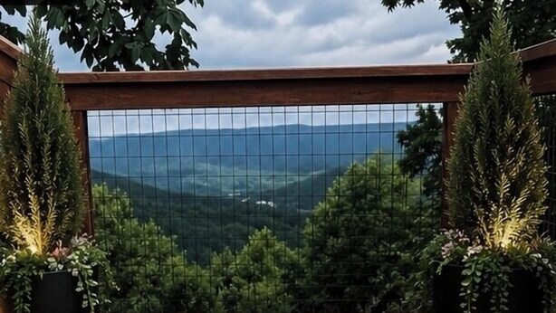 Eine Holzterrasse mit Fußmatte mit der Aufschrift 'Mountain Bluff', Blumentöpfen und einer Laterne.