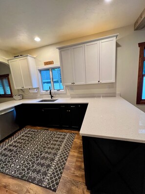 A kitchen with white cabinets, a black countertop, and a patterned rug.