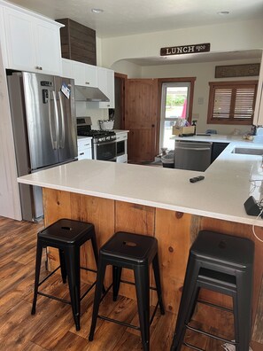 A modern kitchen with a central island, stainless steel appliances, and a wooden door.