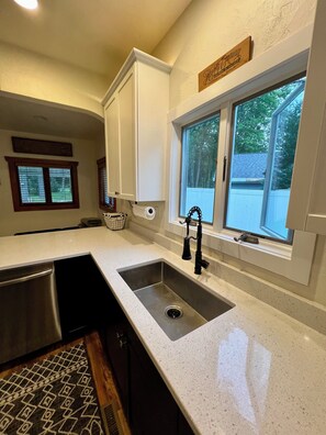 A kitchen with a double sink, a window with a view, and a countertop.