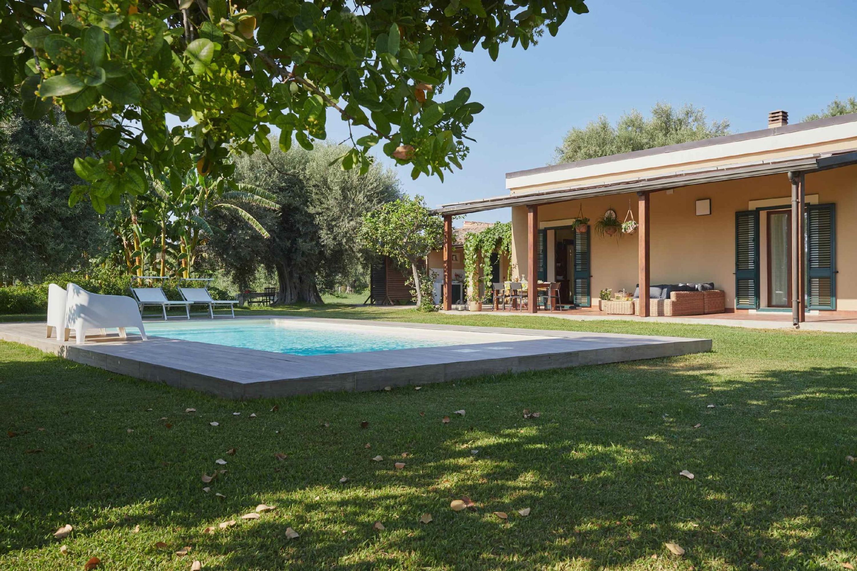 Una casa moderna con piscina, zona de estar exterior y jardín.