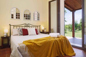 Ein Schlafzimmer mit einem Bett, zwei Nachttischen, einem Fenster und Blick auf einen Garten.