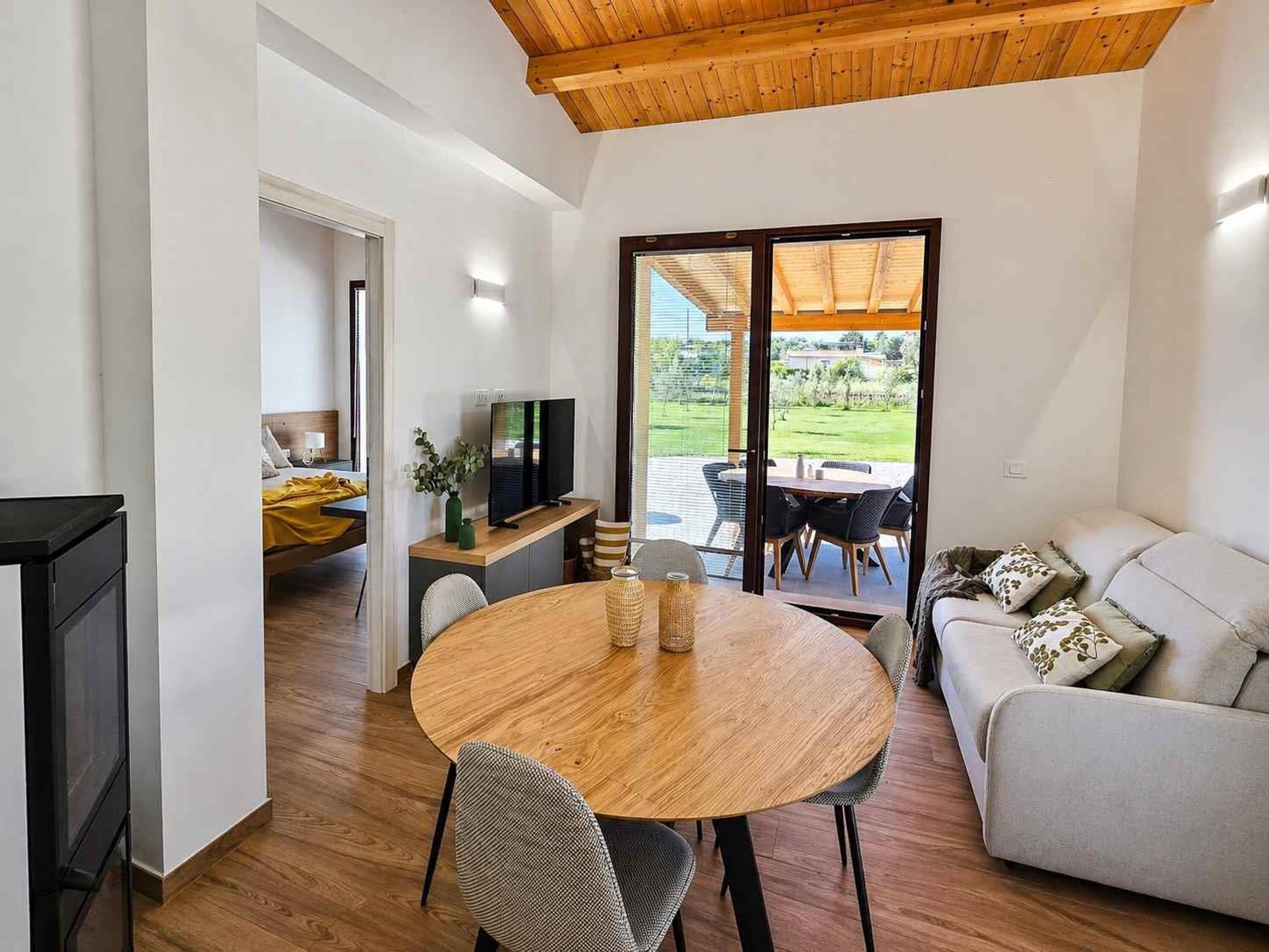 Un salon moderne avec un plafond en bois, une table de salle à manger ronde, un canapé et un téléviseur.