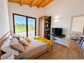 Ein Schlafzimmer mit Bett, Schreibtisch, Fernseher und Blick ins Freie.