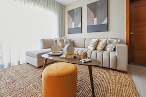 Una sala de estar con sofá, reposapiés, mesa de centro y objetos decorativos.