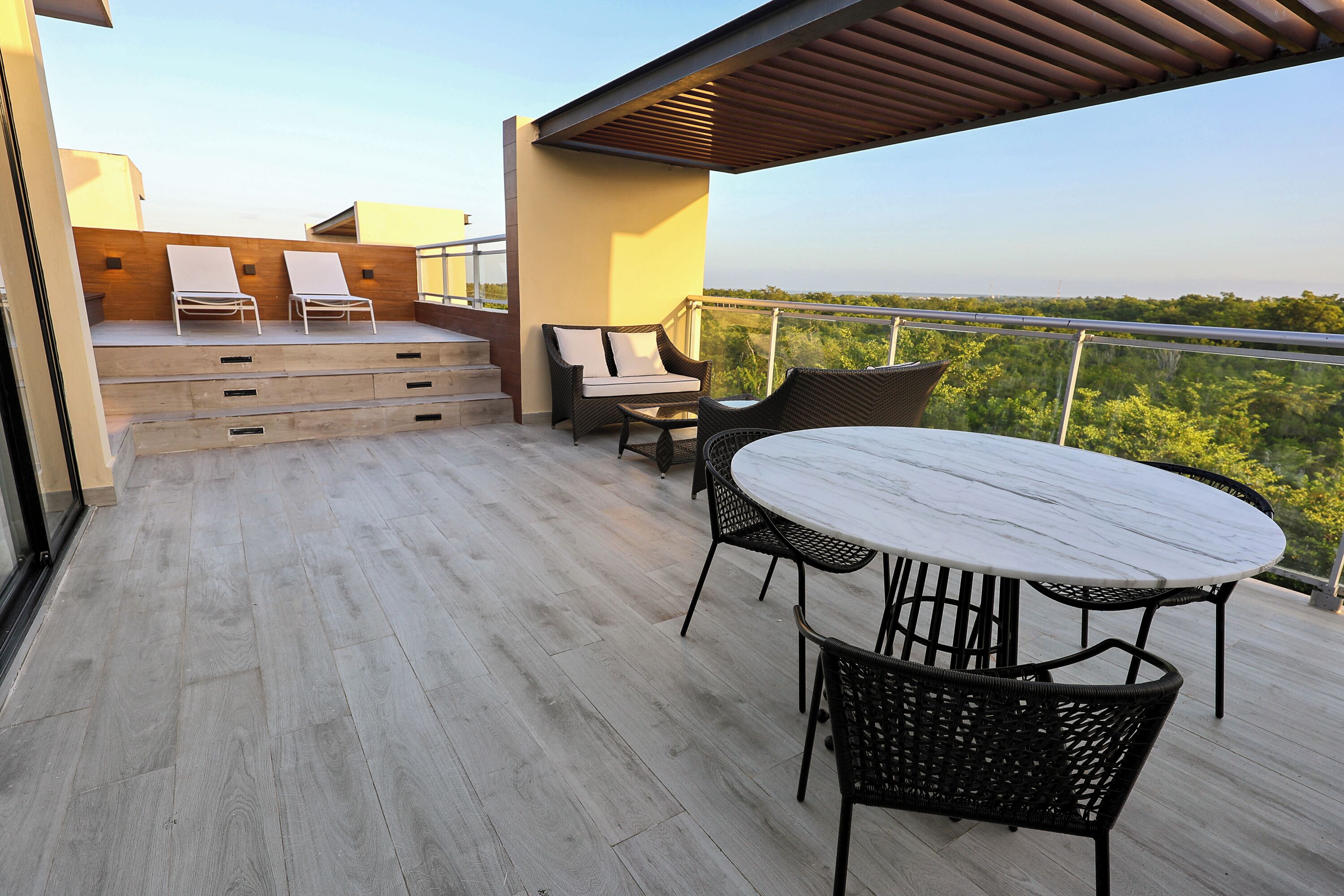 Un balcon doté d’un plancher en bois, d’une table ronde et de deux fauteuils de relaxation.