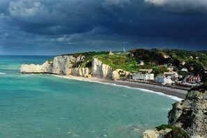Une ville côtière avec des falaises, un phare et des bâtiments qui bordent la plage.
