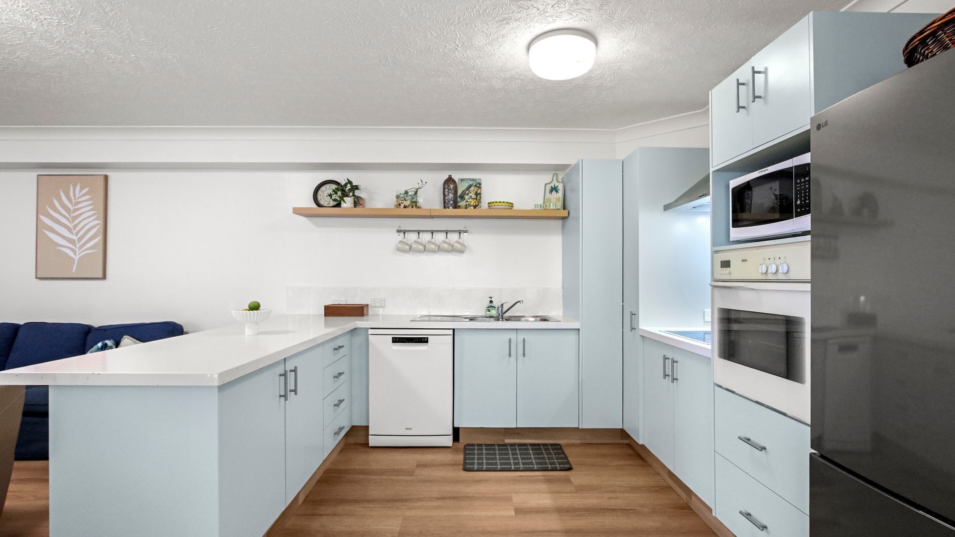 Une cuisine moderne avec des meubles blancs, un lave-vaisselle encastré, un four à micro-ondes et un réfrigérateur.