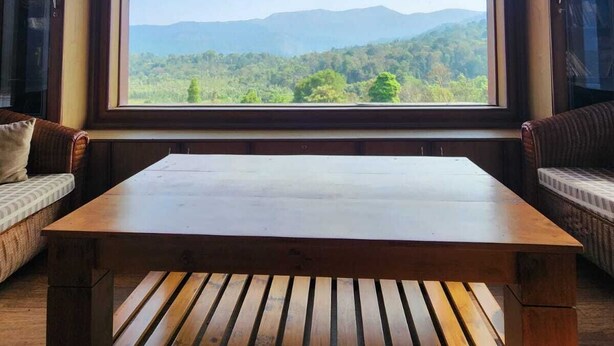 Una habitación con un ventanal grande, una mesa de madera y dos sofás.