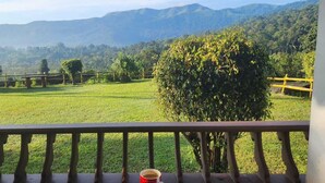 Un balcón con vistas a un campo verde y montañas distantes.