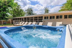 Ein Whirlpool mit Pool, Liegestühlen und einem Gebäude mit Fenstern im Hintergrund.