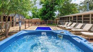 A hot tub with a wooden deck and lounge chairs. - Girls Trip Getaway | Pool + Spa Near Main Street (Fredericksburg)