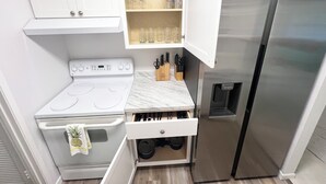 A compact kitchen with a white stove, a stainless steel refrigerator, and a cabinet with wine glasses. - Heated pool home with a lake view! (St. Augustine)