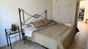 Una camera da letto con un letto, un comodino, una ventola a soffitto e un armadio.