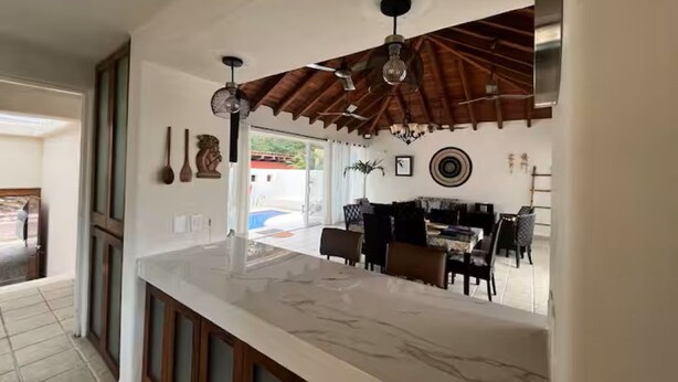 Una cucina con piano di lavoro in marmo, mobili in legno e una ventola a soffitto.