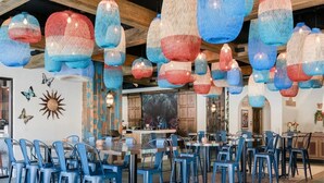 Ein Restaurant mit blauen Stühlen, Tischen und hängenden roten und blauen Laternen.