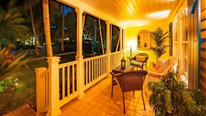 A covered outdoor area with a wooden railing, wicker furniture, and potted plants. - Palm Ridge House w/ Pool and Cabana Near Beach (West Palm Beach)