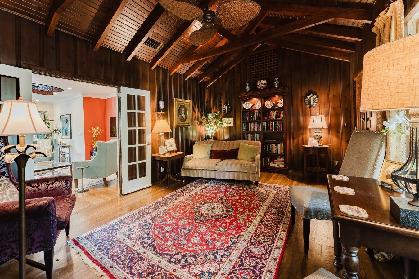 Une pièce chaleureuse avec un plafond en bois, un canapé, une table basse, une bibliothèque et un tapis à motifs.