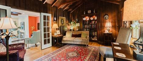 Une pièce chaleureuse avec un plafond en bois, un canapé, une table basse, une bibliothèque et un tapis à motifs.