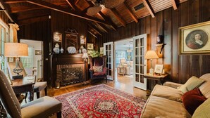 A traditional room with a fireplace, wooden beams, and a red patterned rug. - Palm Ridge House w/ Pool and Cabana Near Beach (West Palm Beach)