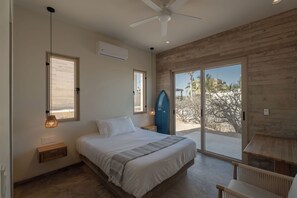 Ein Schlafzimmer mit Bett, Nachttisch, Lampe und Blick durch eine Schiebetür.
