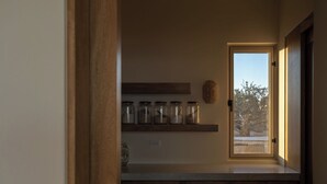 A kitchen with wooden cabinets, a countertop, and a window with a view of trees. - Luxury Ocean View, Modern Mexican Design + Epic Views
5 bedrooms, Sleeps 16 (playa tortuga)