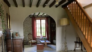 Una sala acogedora con una mesa de madera, un sofá, una escalera y una pared de piedra.