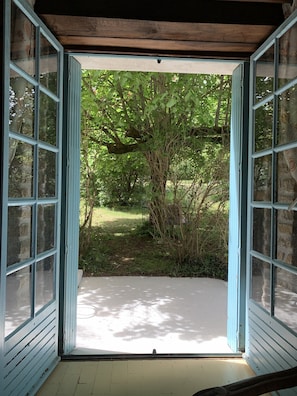 Une pièce dotée d’une grande fenêtre ouverte donnant sur un jardin.
