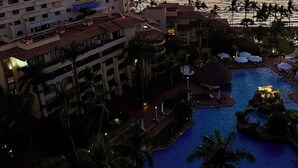 Un resort con piscina, palmeras y vistas al atardecer.
