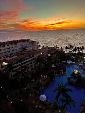 Ein Resort mit Pool, Palmen und Blick auf den Sonnenuntergang.